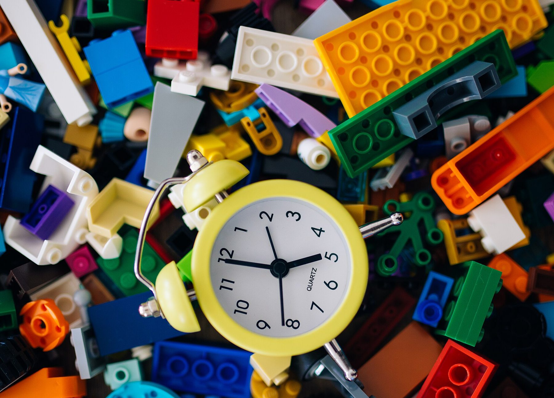 Colorful building blocks scattered around a small alarm clock