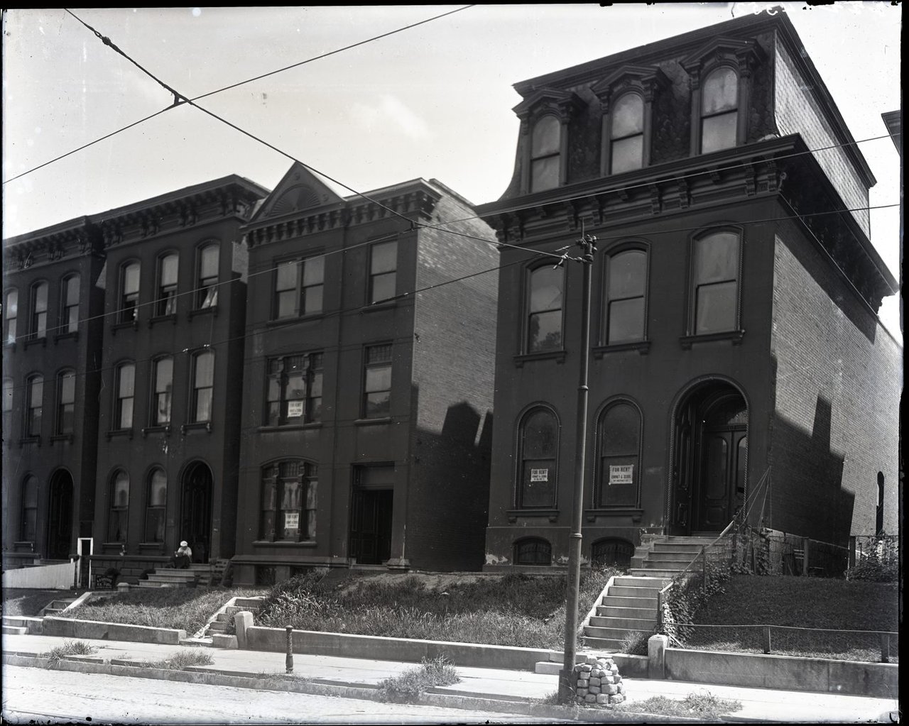 A row of historic apartment buildings with For Rent signs in the windows