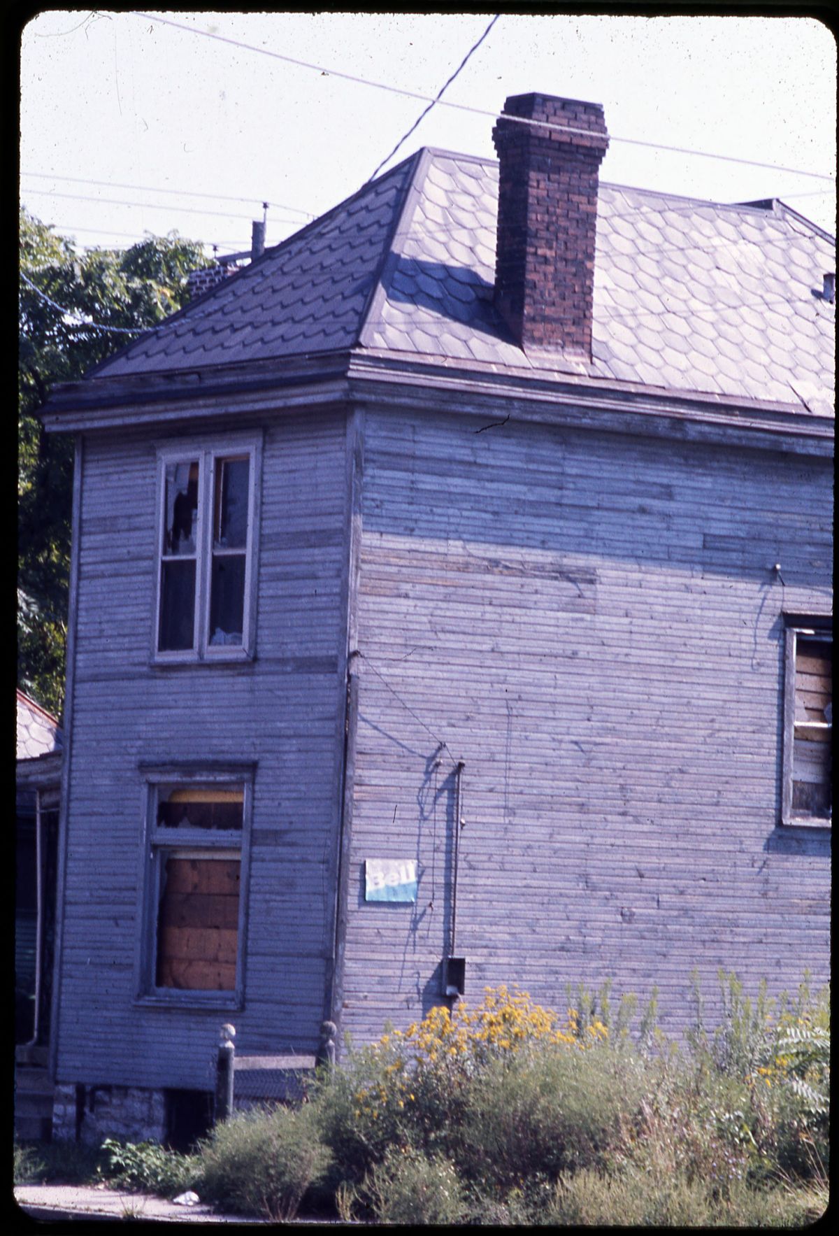 A vacant wood-frame house with boarded and broken windows