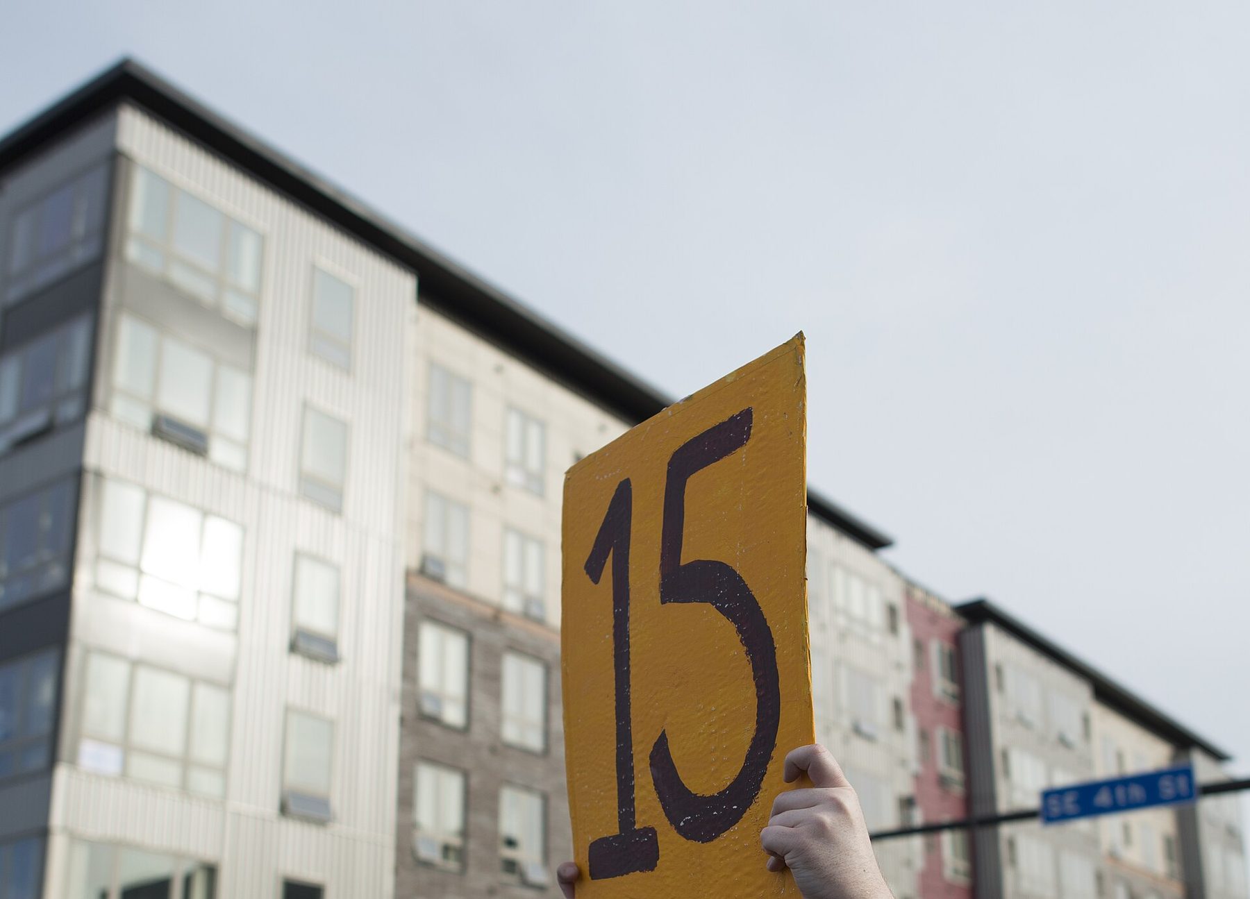 A protester holds up a hand-painted sign reading '15' at a Fight for $15 minimum wage rally