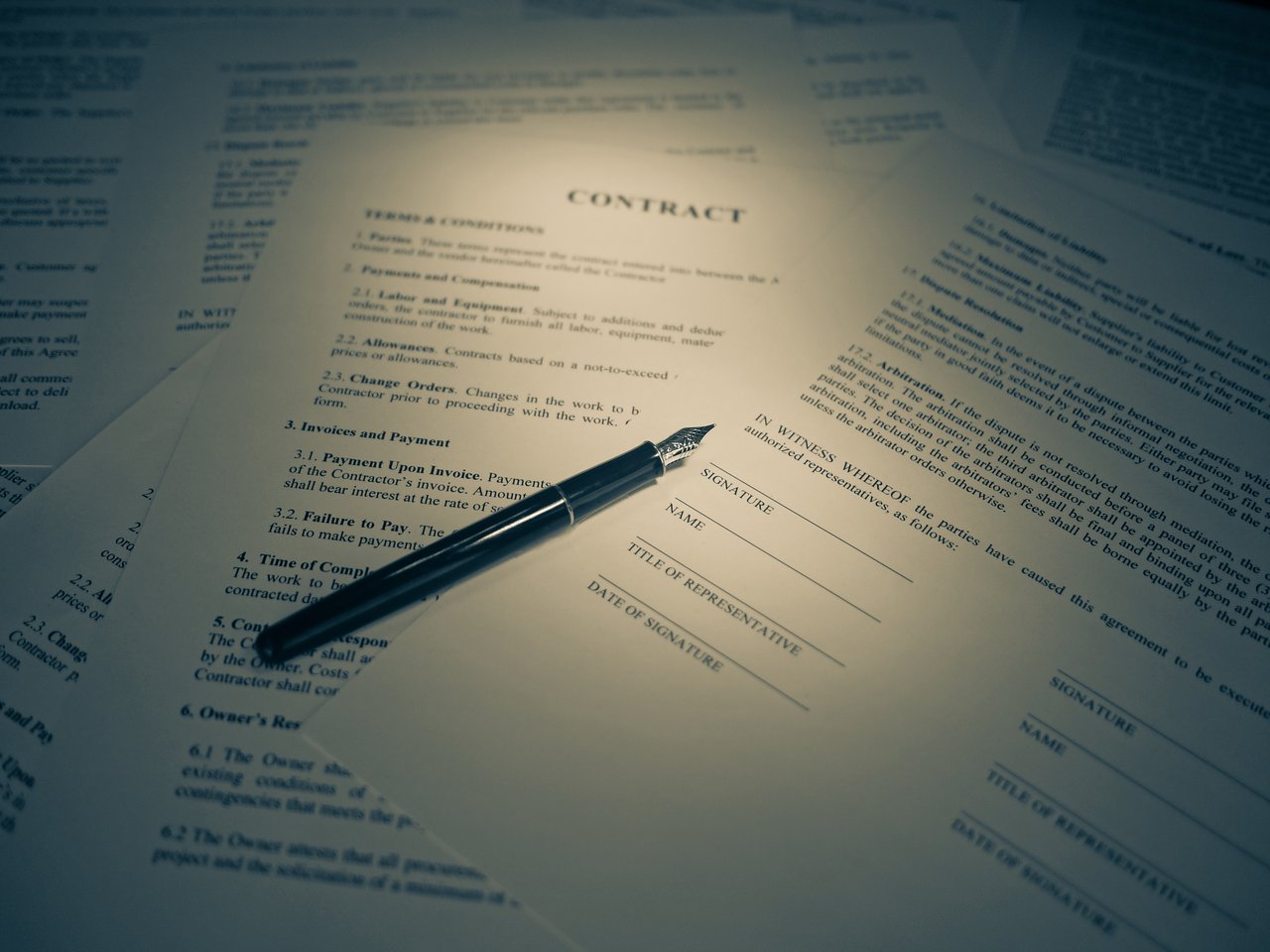 A fountain pen resting on an unsigned paper contract with blank signature lines