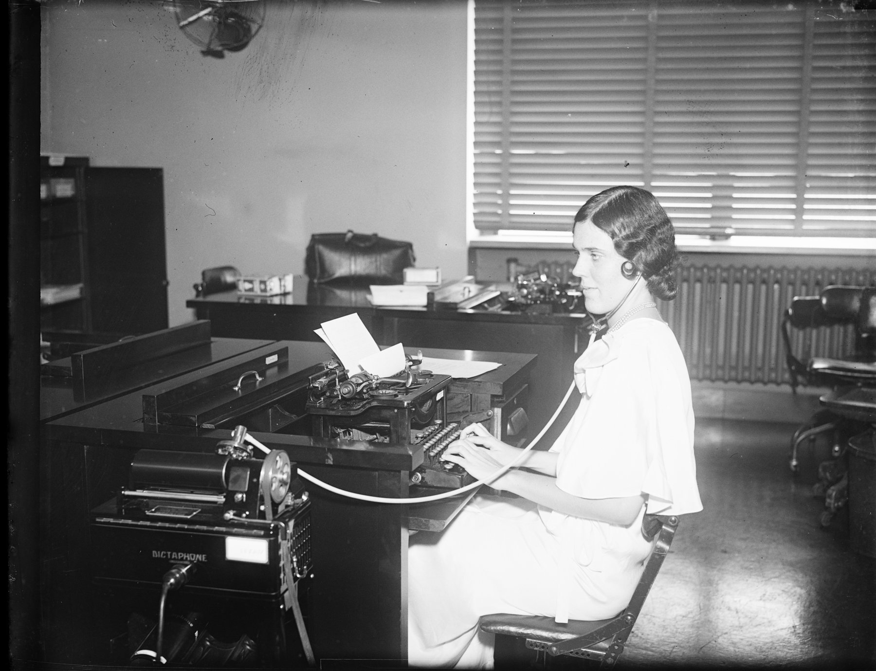 A woman working at a typewriter in an office, historical photograph