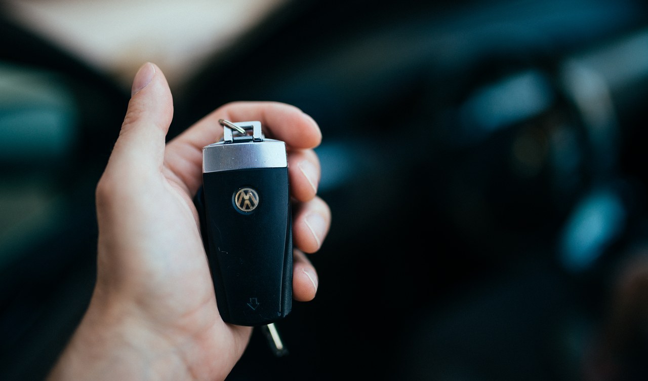 A hand holding a car key fob inside a vehicle