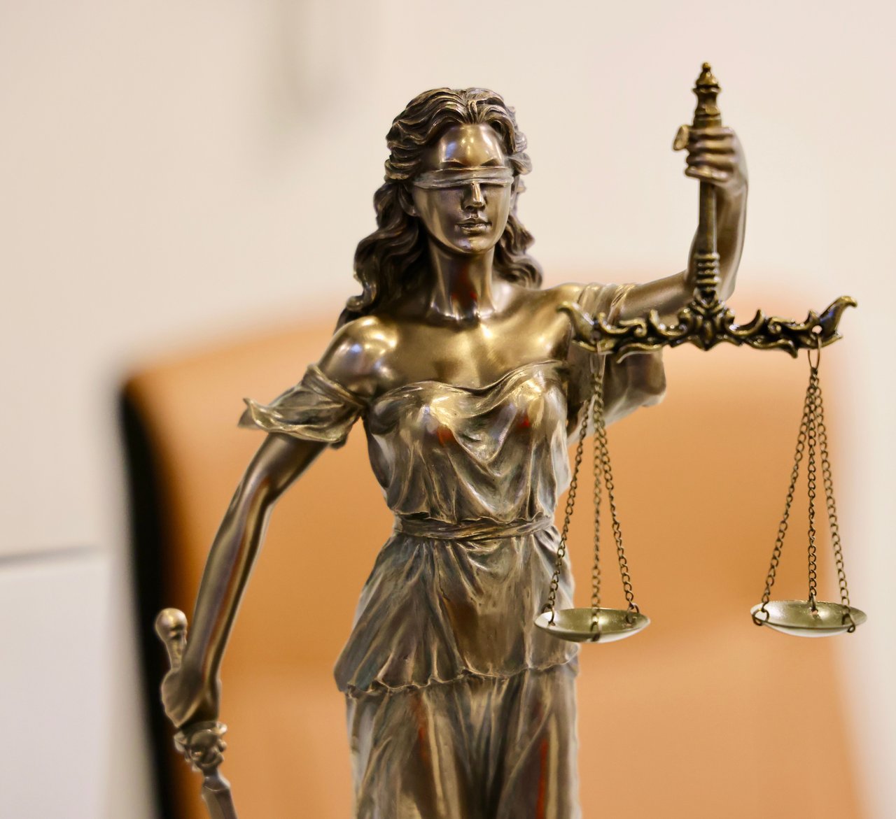 A bronze Lady Justice statuette holding a blindfold and a set of scales