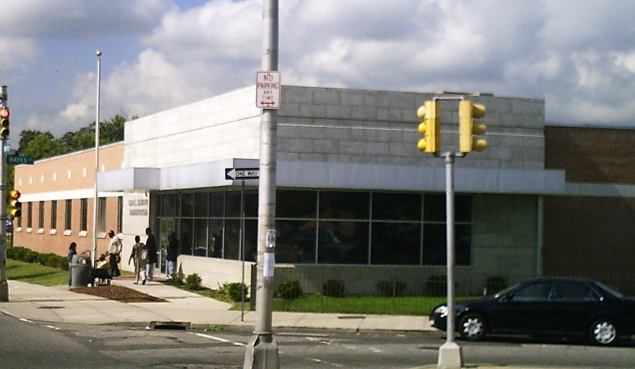A Social Security Administration field office building with people waiting outside the entrance